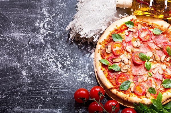 pizza with ham and vegetables on dark background
